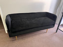 Black sofa on a carpeted floor with a neutral wall background