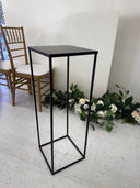 Modern black metal staircase with floral decoration on a white wall.