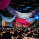 Dinner event with colorful drapery and table settings.