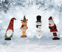Set of Christmas-themed garden stakes including a gnome, reindeer, snowman, and Santa Claus against a snowy background.