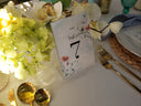 Table setting with floral centerpiece, table number, and cutlery on a white tablecloth.