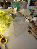 Decorative table setting with flowers, glasses, and cutlery on a white surface.