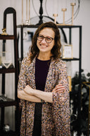 Woman wearing glasses and a patterned coat standing in an interior design store.