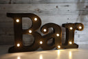 A brown light-up bar sign with illuminated letters displaying the word 'Bar'.