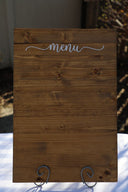 A wooden menu board with a white text displaying the word 'menu' on a plain background.
