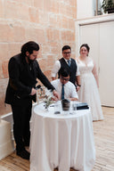 Group of people gathered around a table with a white tablecloth in an indoor setting. Signing Marriage license