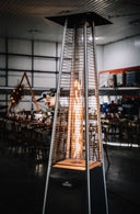 Tall outdoor heater with flames inside, set against a warehouse background.