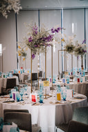 Decorated event space with round tables, floral centerpieces, and chairs.