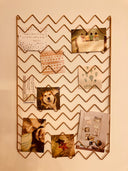 A rose gold seating chart display board with zigzag design, hanging on a wall and showcasing various cards or documents.