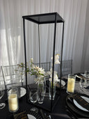 Modern black dining table with glass chairs and white flowers on a neutral background
