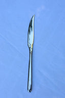 A single steak knife with a stainless steel finish placed on a blue surface.