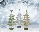 Three glittery Christmas trees on stands against a snowy background with pine branches.
