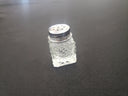 Clear textured saltshaker with silver top on a black surface