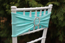 A tiffany blue chair band with a broach decoration on a white chair.