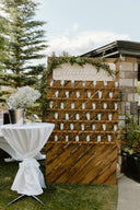 Wooden wall with decorative elements and 'Chambers' sign, outdoor setting with table and plants.