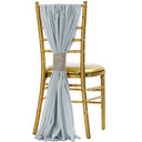 A dusty blue chiffon chair sash tied with a ribbon on a golden chair.